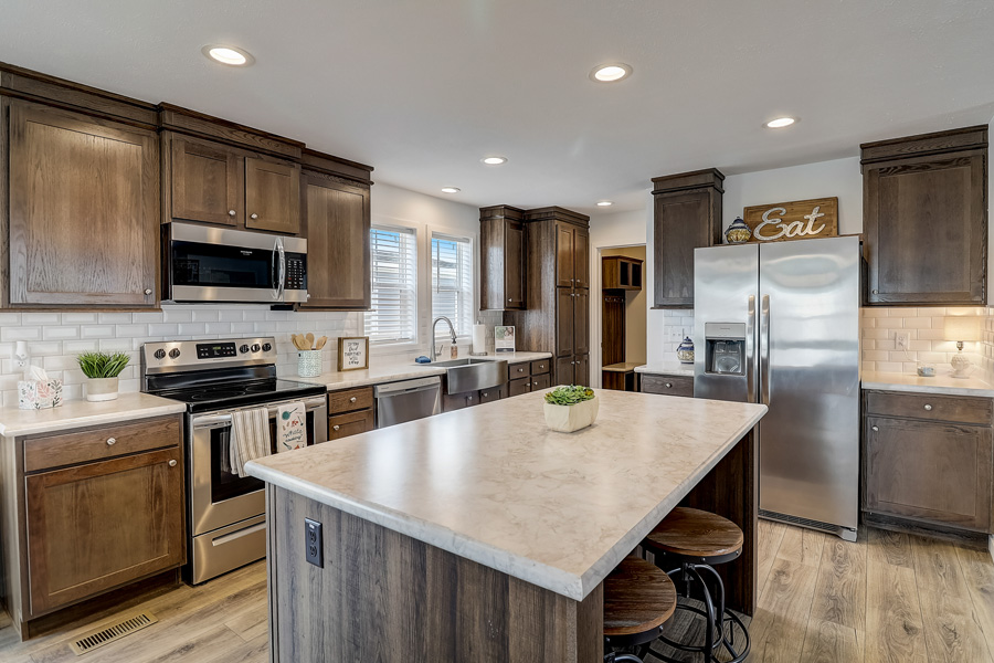 Modern manufactured home kitchen featuring a large island, wood cabinetry, stainless steel appliances, and recessed lighting